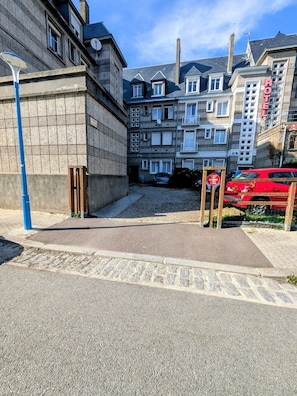 A street view with a red car parked on the right, a blue street lamp on the left, and a building with a sign that reads 'HOTEL' in the background. - right by the sea (Saint-Valery-en-Caux)