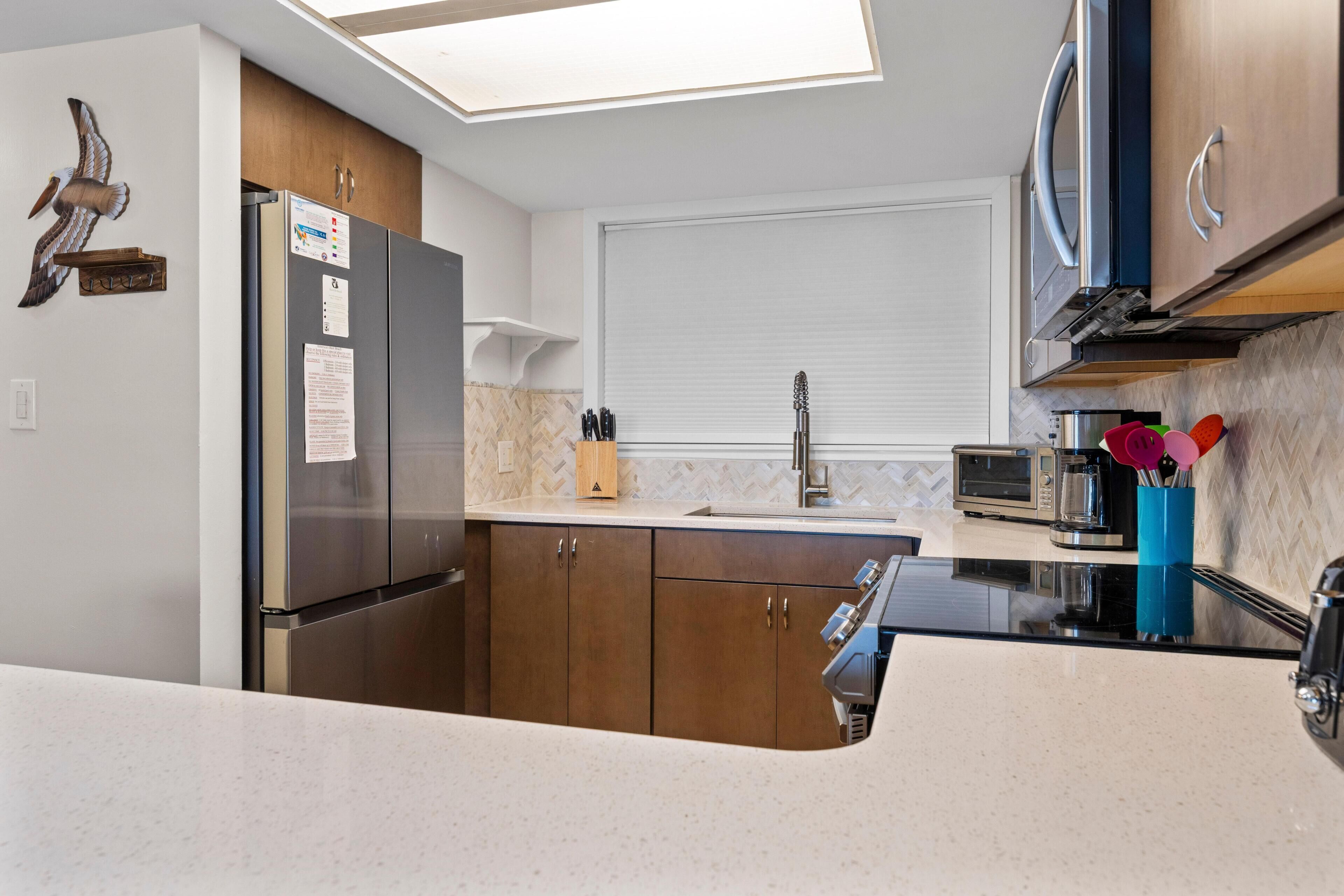 Una cocina moderna con microondas integrado, refrigerador de acero inoxidable y armarios de madera.