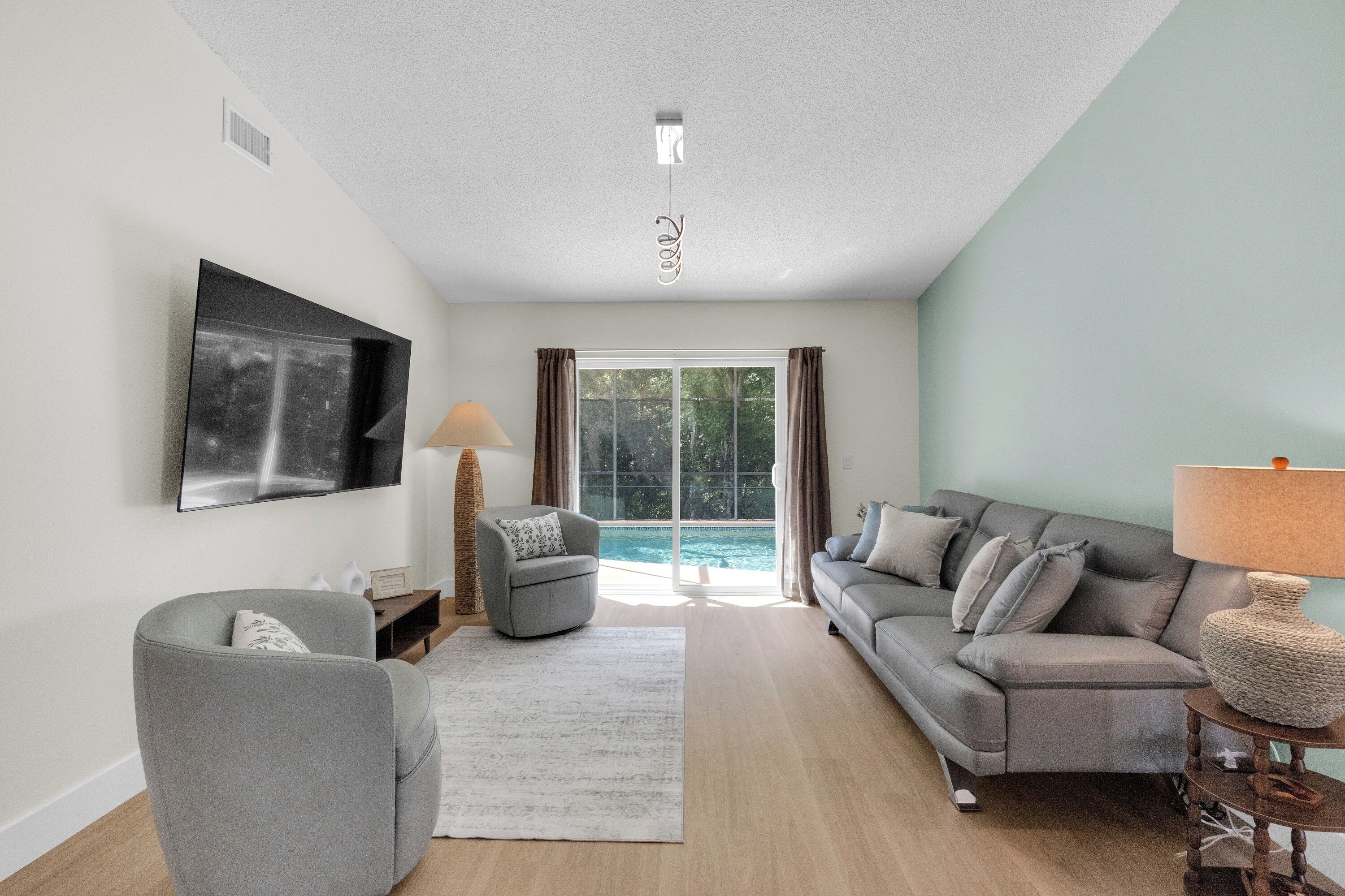 A modern living room with a sofa, armchair, and a flat-screen TV.