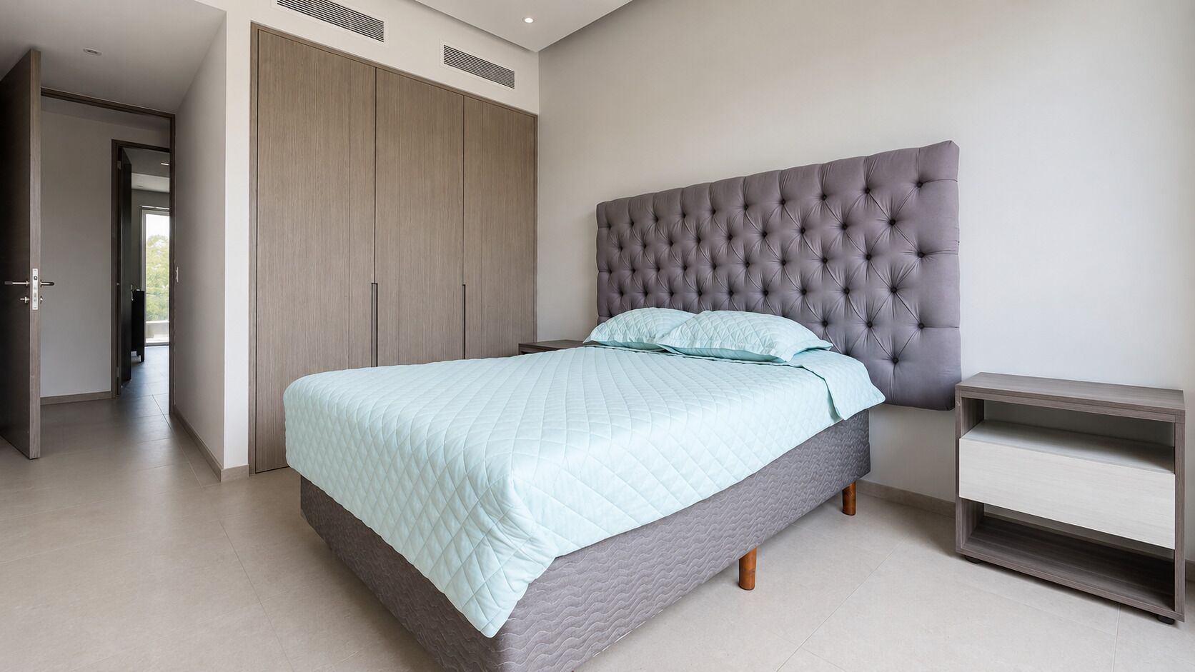A bedroom with a bed, a wardrobe, and a bedside table.