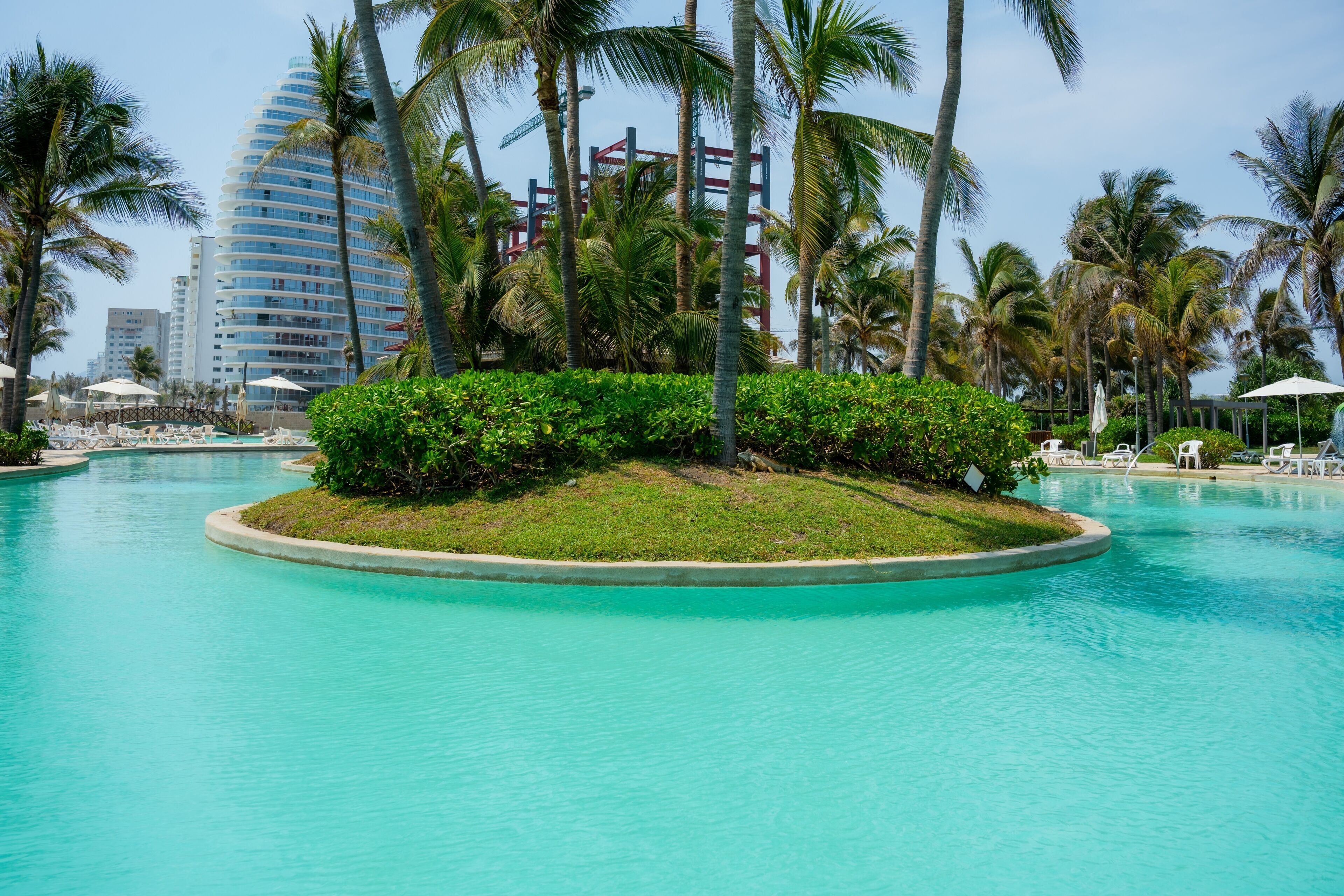 Una piscina rodeada de palmeras y un edificio moderno al fondo.