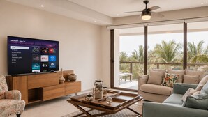 A modern living room with a flat-screen TV, wooden furniture, a coffee table, and a balcony with palm trees. - Depto. Playa & Piscina Acapulco 4 Rec (Acapulco de Juarez)