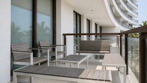 A balcony with outdoor furniture, large windows, and a modern building design. - Depto. Playa & Piscina Acapulco 4 Rec (Acapulco de Juarez)