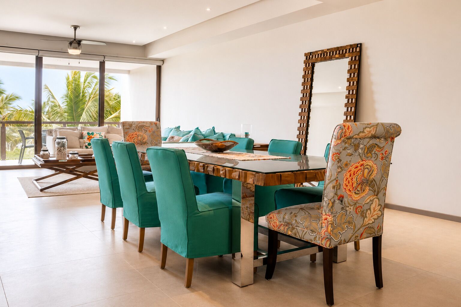 Un coin repas avec une table en bois, des chaises de couleur turquoise et un grand miroir.