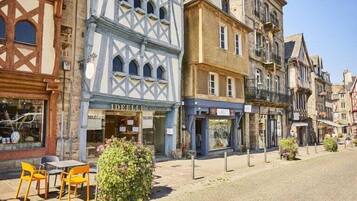 Une rue pavée bordée de bâtiments historiques, dont une boutique dont l’enseigne porte l’inscription « DEELLE ».