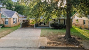 A residential driveway leading to a house with a covered porch and a tree in the foreground. - Jarrel Cottage Longer Stays Welcome! (Tyler)