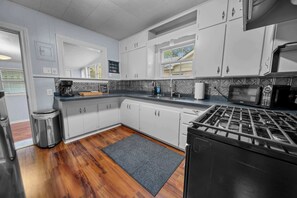 A modern kitchen with white cabinets, a gas stove, a microwave, and a coffee maker. - Jarrel Cottage Longer Stays Welcome! (Tyler)