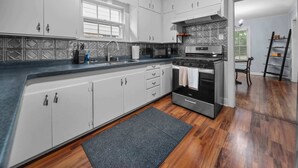 Et moderne køkken med en central ø, rustfrie stålemmer og et mønstret backsplash.