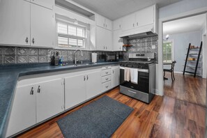 A modern kitchen with a central island, stainless steel appliances, and a patterned backsplash. - Jarrel Cottage Longer Stays Welcome! (Tyler)