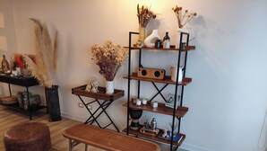 Ein Zimmer mit einer Bank, einem kleinen Tisch, einem Regal mit Dekoration und einem gemusterten Teppich.
