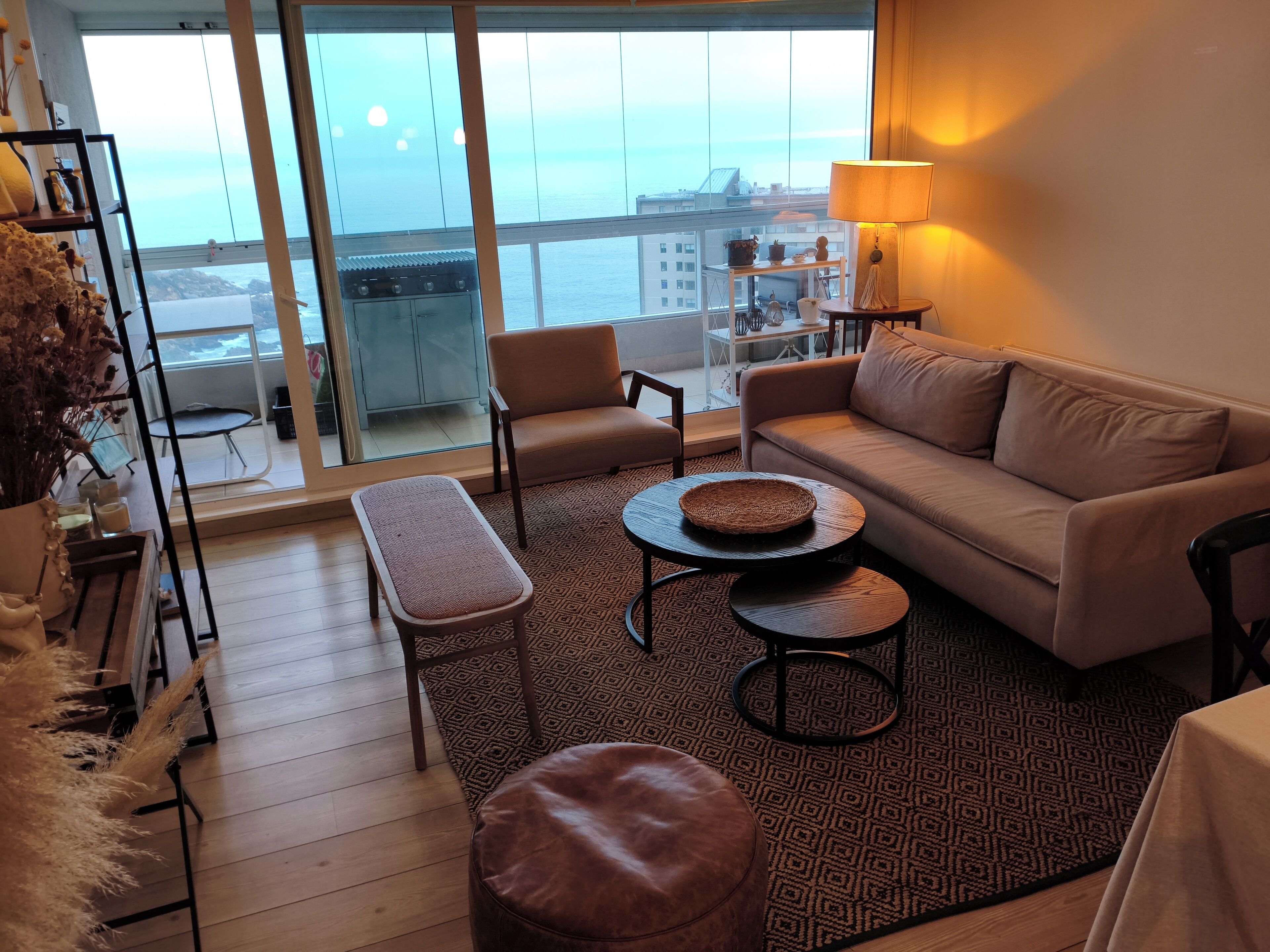A modern living room with a sofa, two chairs, a bench, a coffee table, and a lamp.