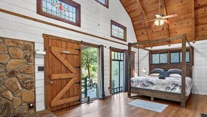 Ein Schlafzimmer mit Himmelbett, Holzböden, einer Steinwand und einer großen Holztür.