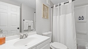 A bathroom with a white sink, toilet, and shower curtain.