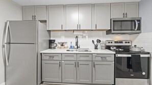 A kitchen with a refrigerator, microwave, stove, and sink.