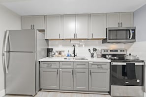 A kitchen with a refrigerator, microwave, stove, and sink.