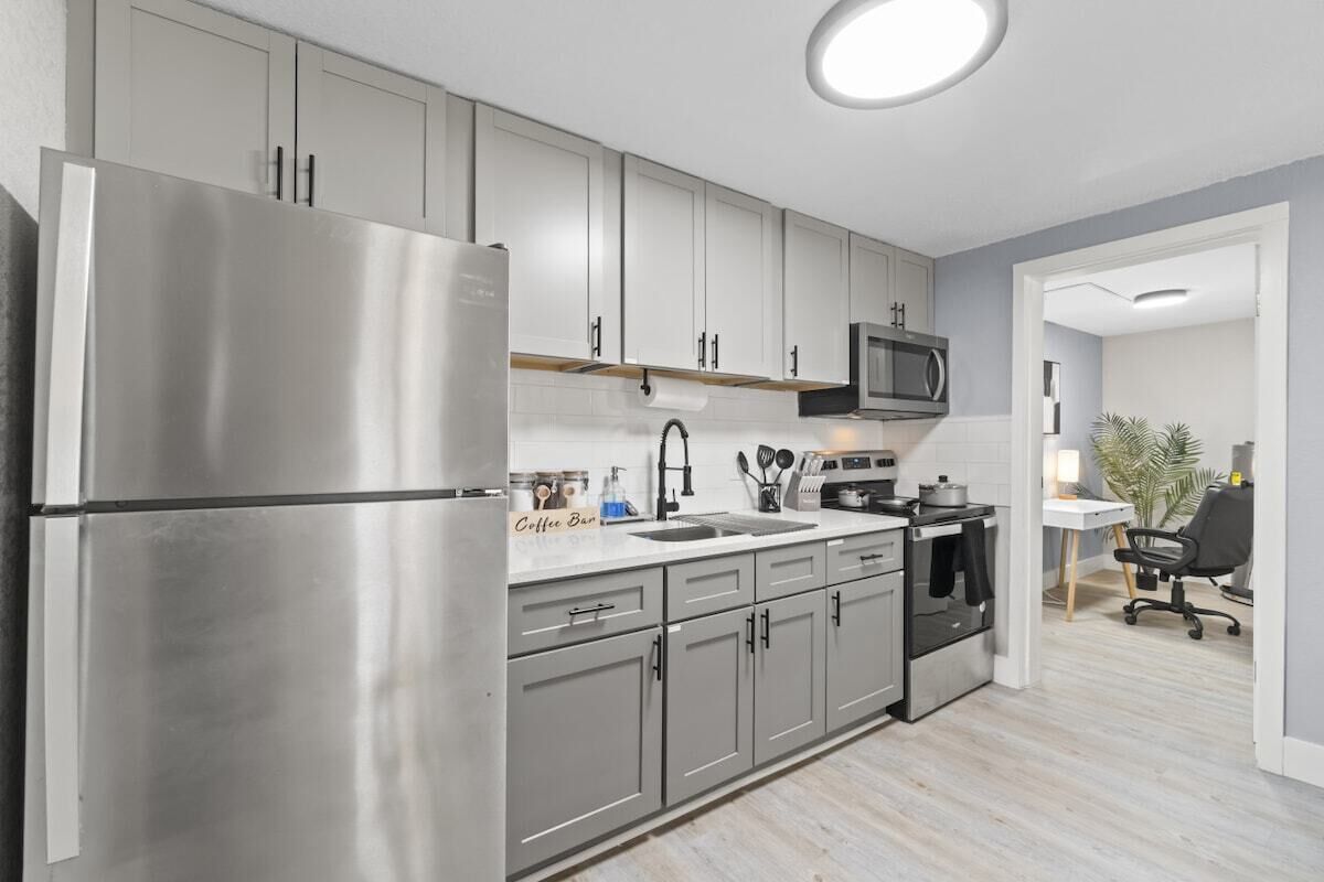 A modern kitchen with stainless steel appliances, grey cabinets, and a microwave.