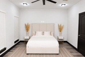 A bedroom with a bed, two bedside tables, a ceiling fan, and a door. - Modern Houston Retreat: Free Parking, Group Friendly, Near Med Center & Downtown (Houston)