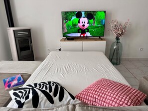 A bedroom with a bed, a television displaying an animated character, a small cabinet, and a vase with flowers. - Family home between Avignon and Mont Ventoux with free EV charging (Pernes-les-Fontaines)