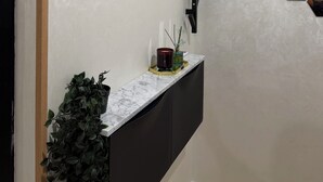 Un interior moderno con una encimera de mármol, una planta en maceta, un candelabro rojo y un estante negro fijado a la pared.