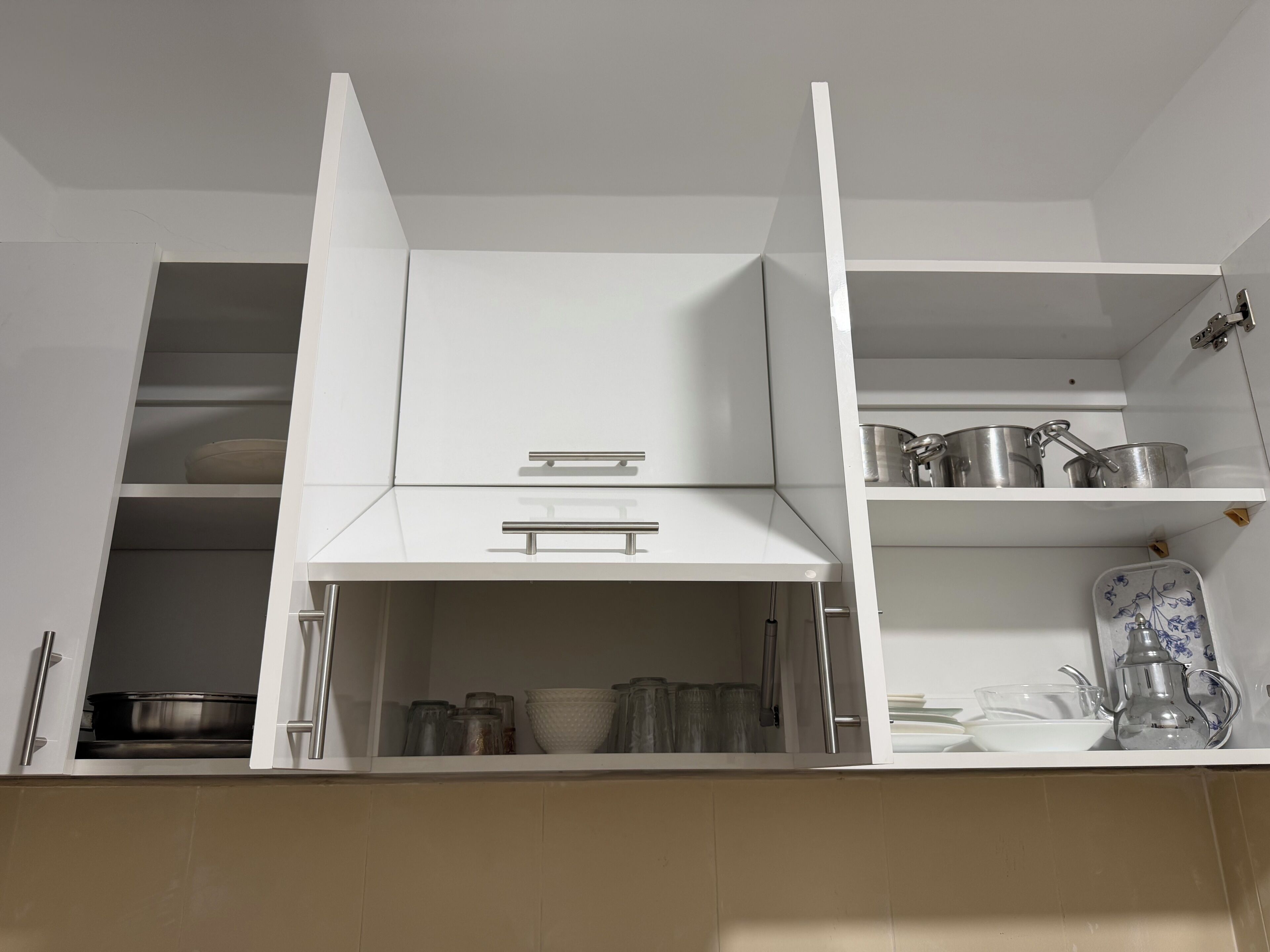 Een keuken met witte kastjes, een aanrecht en diverse keukengerei.