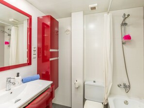 Ein Badezimmer mit Waschbecken, rotem Schrank und Dusche mit Duschbrause.