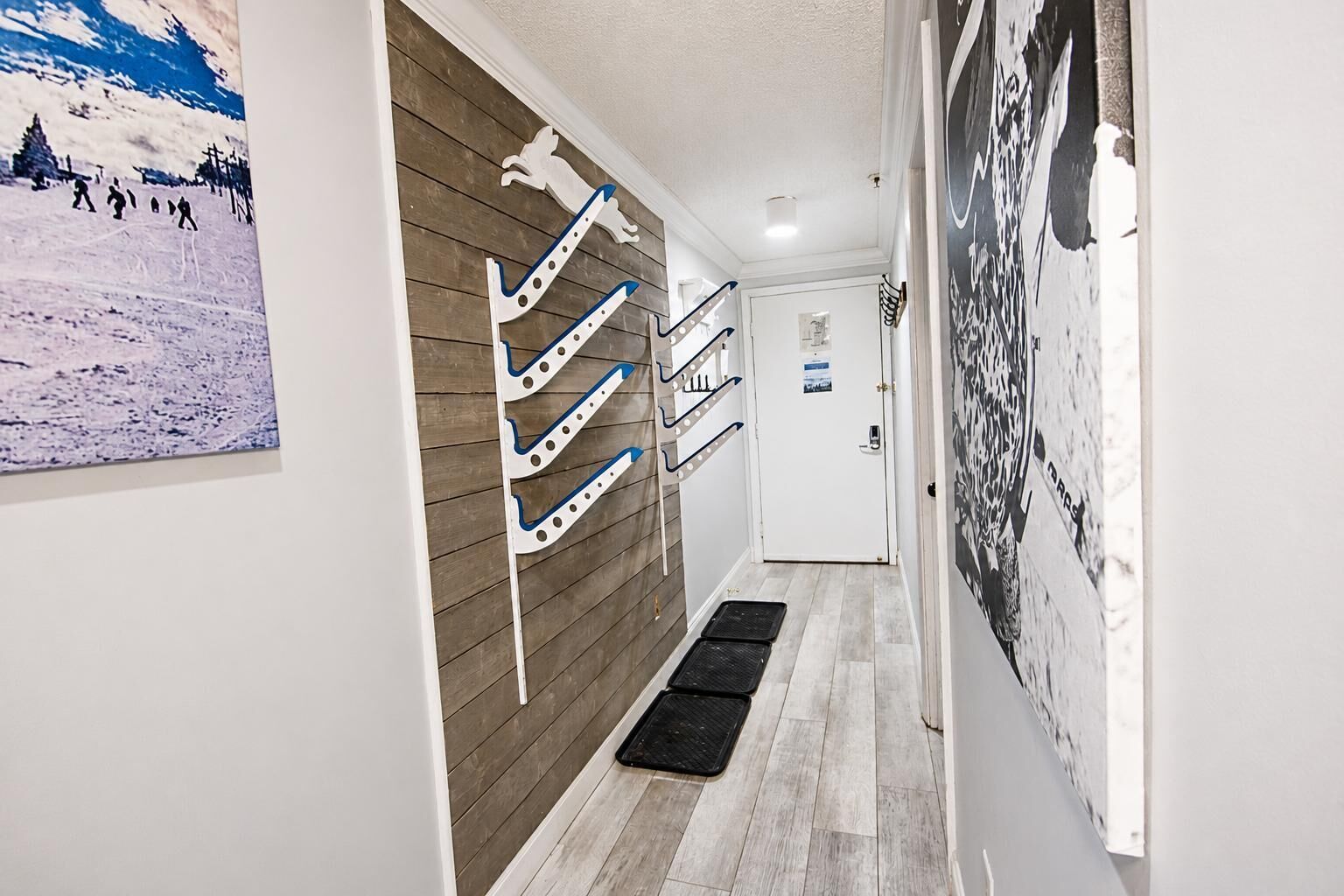 A hallway with a wooden wall, a black mat at the entrance, and a door with a poster.