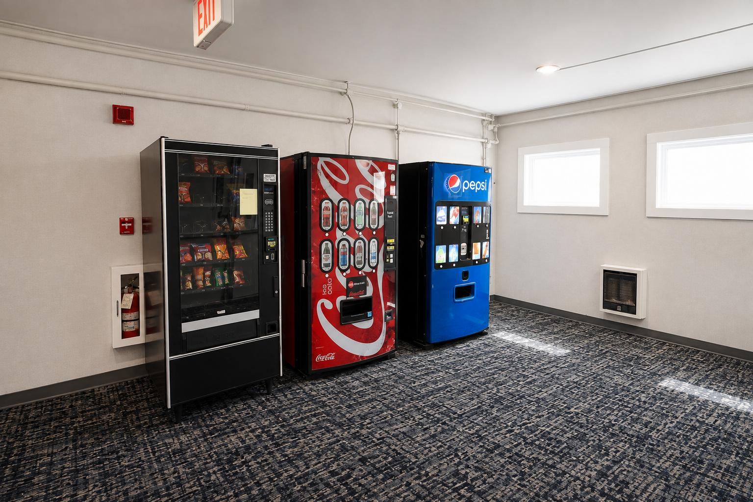 A room with three vending machines, a fire alarm, and a window.