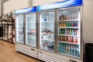 Eine Reihe von Getränkekühlern, gefüllt mit verschiedenen Getränken, darunter Limonaden und Säften, in einem Verkaufsraum.