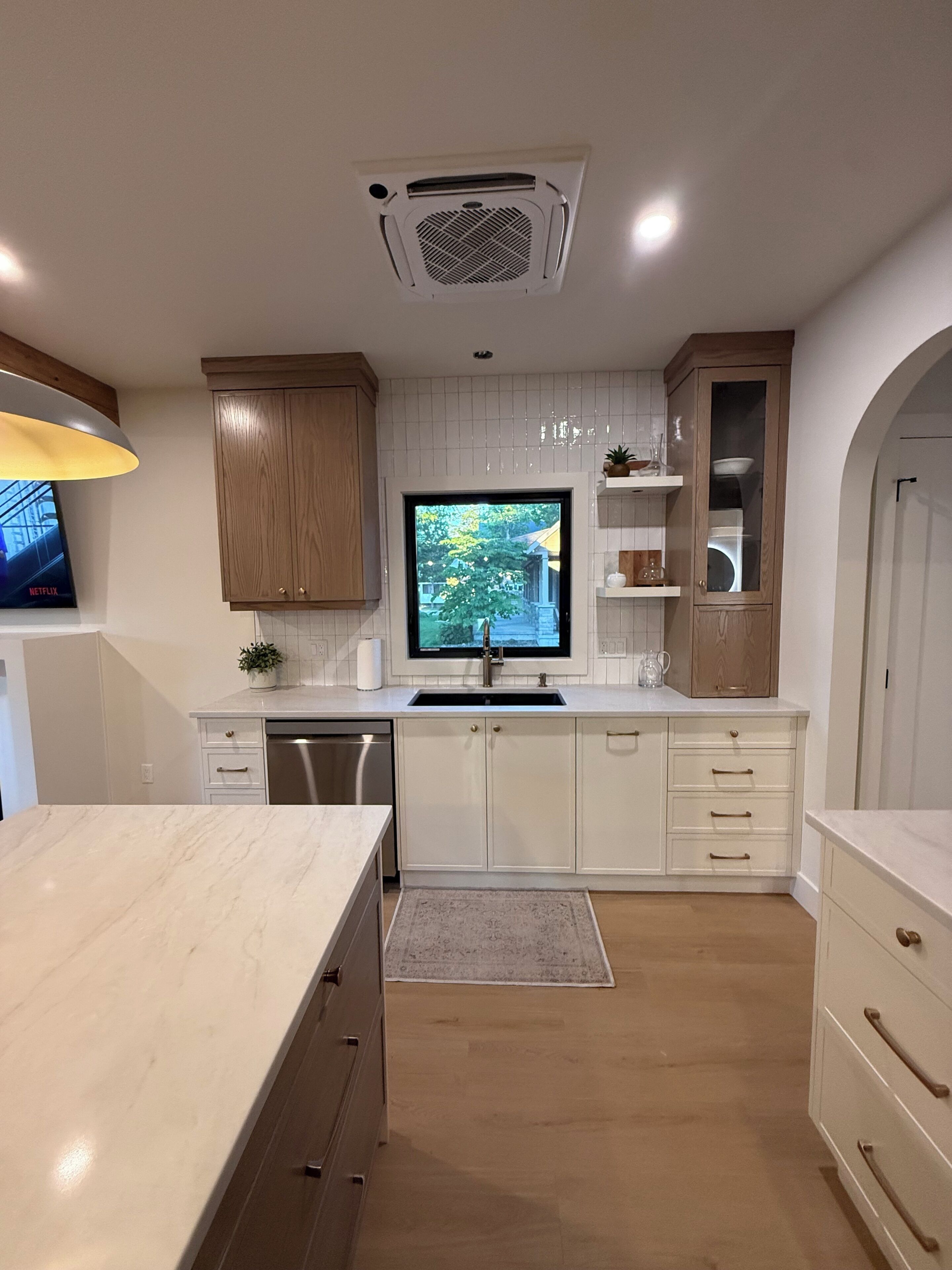 Una cocina moderna con armarios blancos, lavavajillas integrado, un ventanal y vistas al exterior.