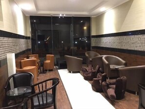 A hotel lobby with a reception desk, seating area with sofas and chairs, and a large glass wall with a view. - Taleen Alsahafa Serviced Apartments (Riyadh)