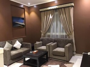 A living room with two sofas, a coffee table, and a painting on the wall. - Taleen Alsahafa Serviced Apartments (Riyadh)