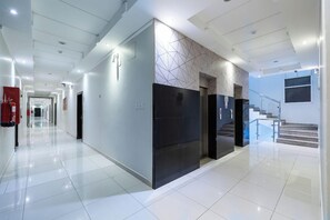 A modern hotel lobby with a long corridor, a staircase, and a fire extinguisher on the left. - Taleen Alsahafa Serviced Apartments (Riyadh)