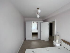 A bedroom with a bed, bedside table, lamp, and a door leading to another room. - Charming for 2, Pitesti downtown 1-bedroom 1-bath apartment with AC (Pitești)