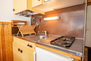 A compact kitchen with a sink, stove, and wooden cabinets. - 250m from ski slopes, 2nd floor, balcony, tv, 23m², La Norma (La Norma)
