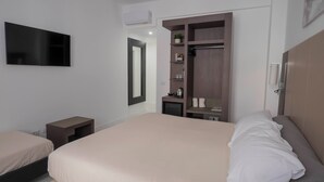 Ein Schlafzimmer mit einem großen Bett, einem Nachttisch, einem Kleiderschrank und einem an der Wand befestigten Fernseher.