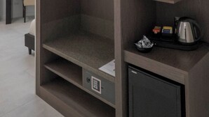 Ein kompaktes Zimmer mit integriertem Kleiderschrank, einer kleinen Küchenzeile und einer Sitzecke.