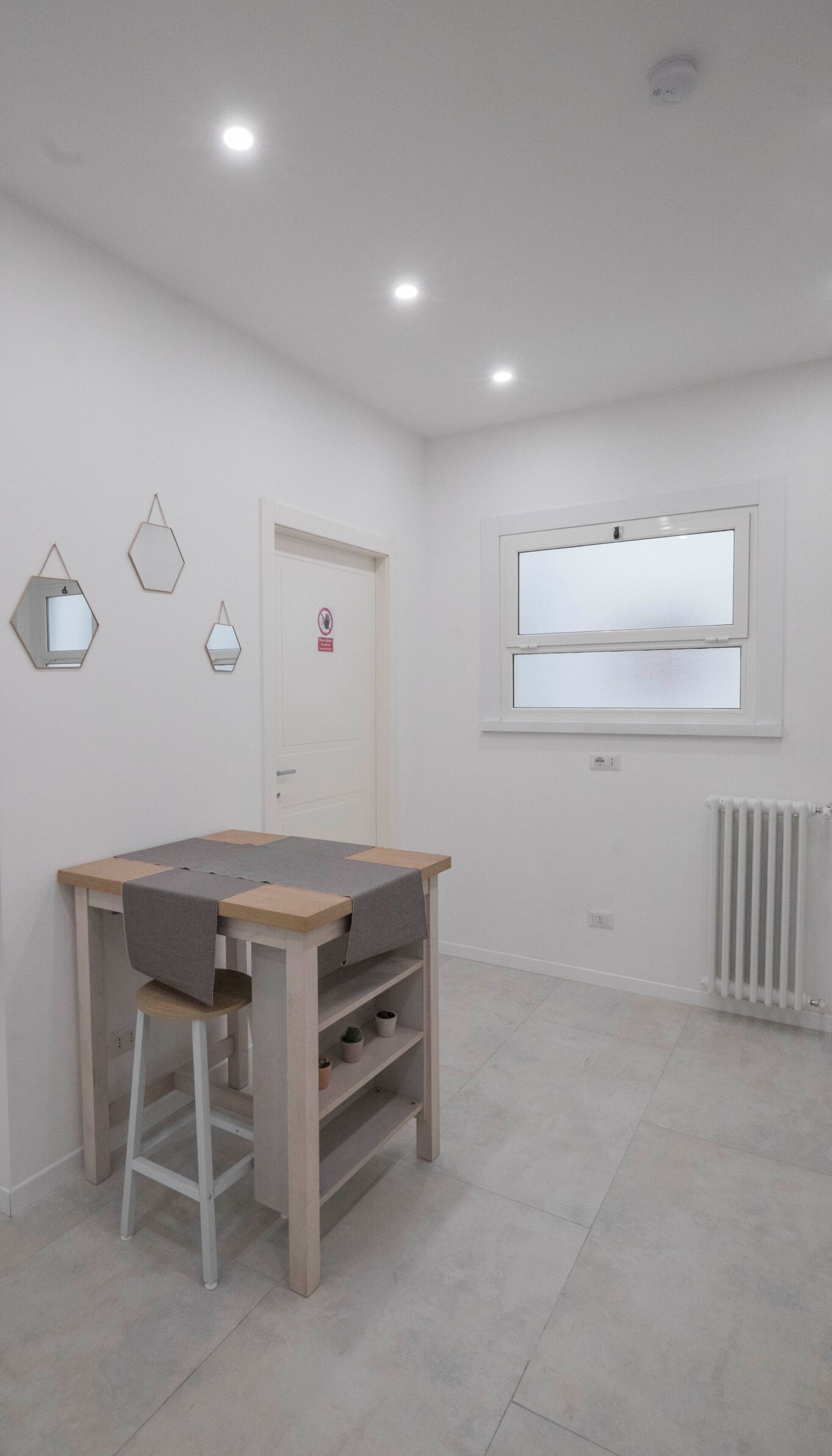 A room with a wooden desk, a stool, and a radiator.
