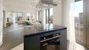 Una cucina moderna con isola centrale, zona pranzo con divano e sedie, e un'ampia finestra vista città.