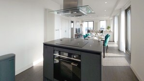 Una cucina moderna con isola centrale, forno integrato e cappa aspirante in acciaio inossidabile.