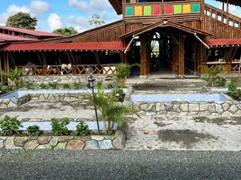 Un edificio de madera tradicional con techo rojo, sendero de piedra y pequeñas plantas.