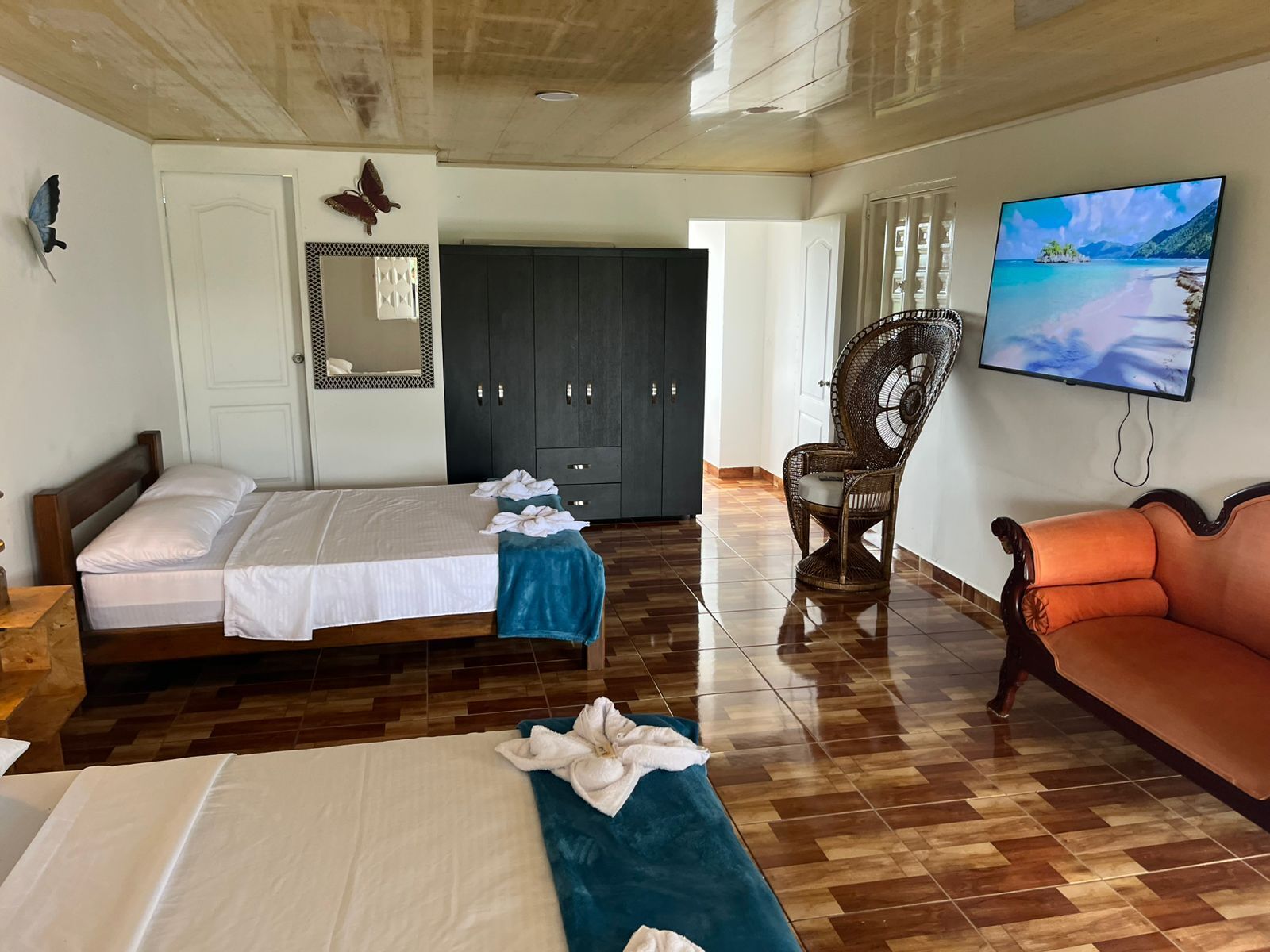 Una habitación de hotel con cama, una silla, un sofá, un televisor y un armario.