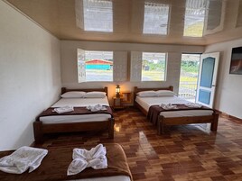 Una habitación con dos camas, suelo de madera y ventana con vistas a un edificio.