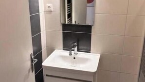 A bathroom with a white sink, a mirror, and a towel rack. - Apartment 5 minutes from the Nancy train station (Nancy)