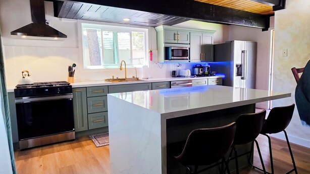 Una cucina moderna con isola centrale, elettrodomestici in acciaio inossidabile e sgabelli da bar.