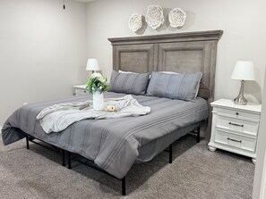 A bedroom with a bed, nightstands, a dresser, a vase with flowers, and wall decorations.