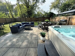 A backyard with a hot tub, outdoor furniture, and a barbecue grill.