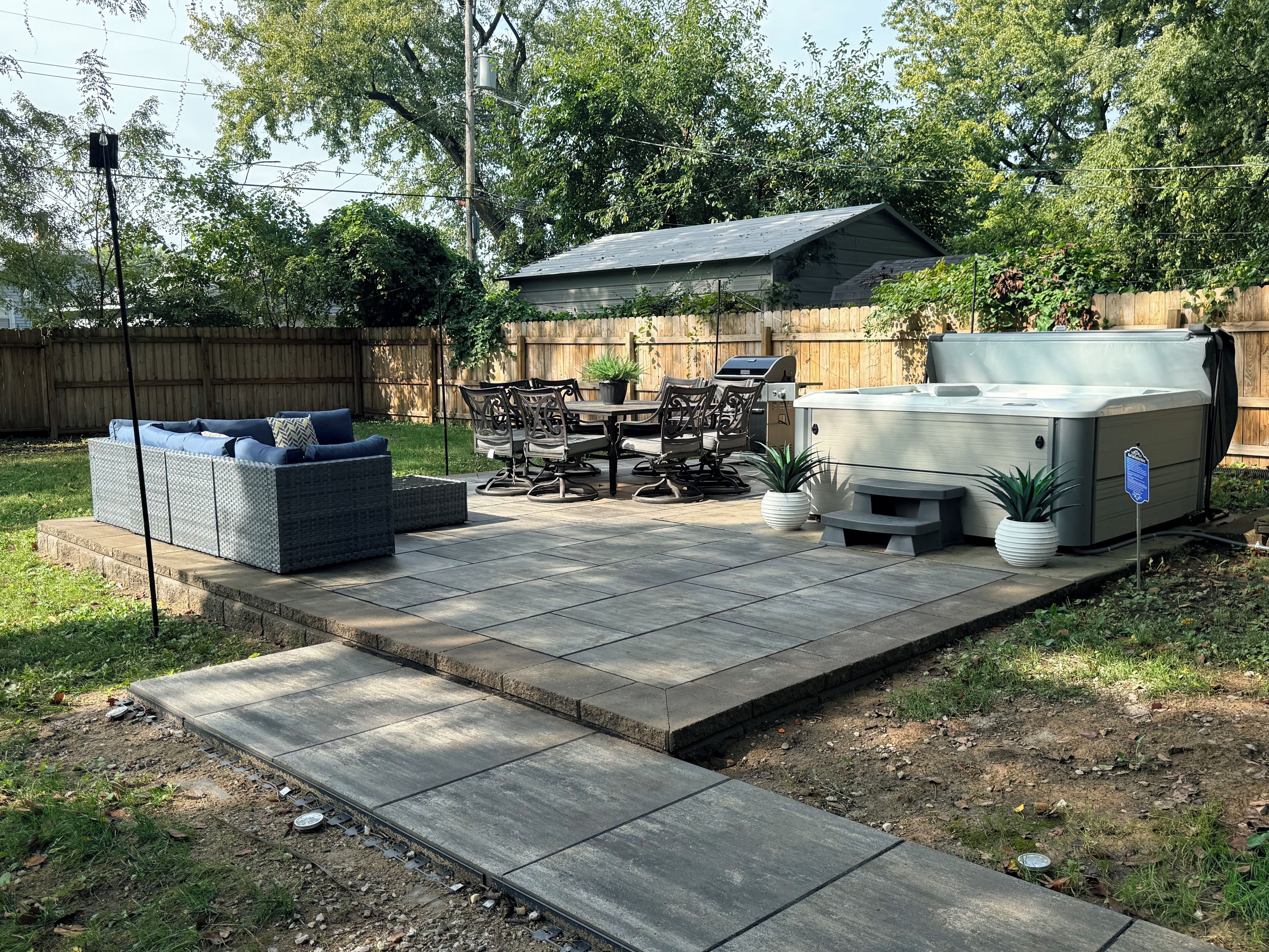 Une terrasse à l’arrière de la maison, avec un barbecue, du mobilier d’extérieur et un jacuzzi.