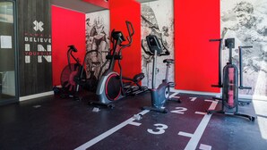 Un gimnasio con bicicletas estáticas, una bicicleta fija y una máquina de remo.