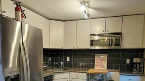 Ett modernt kök med vitvaror i rostfritt stål, en mikrovågsugn och en vattenautomat.