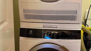 En kombinerad tvätt- och torkmaskin där maskinerna är staplade ovanpå varandra, med en kontrollpanel och ett vatteninlopp.